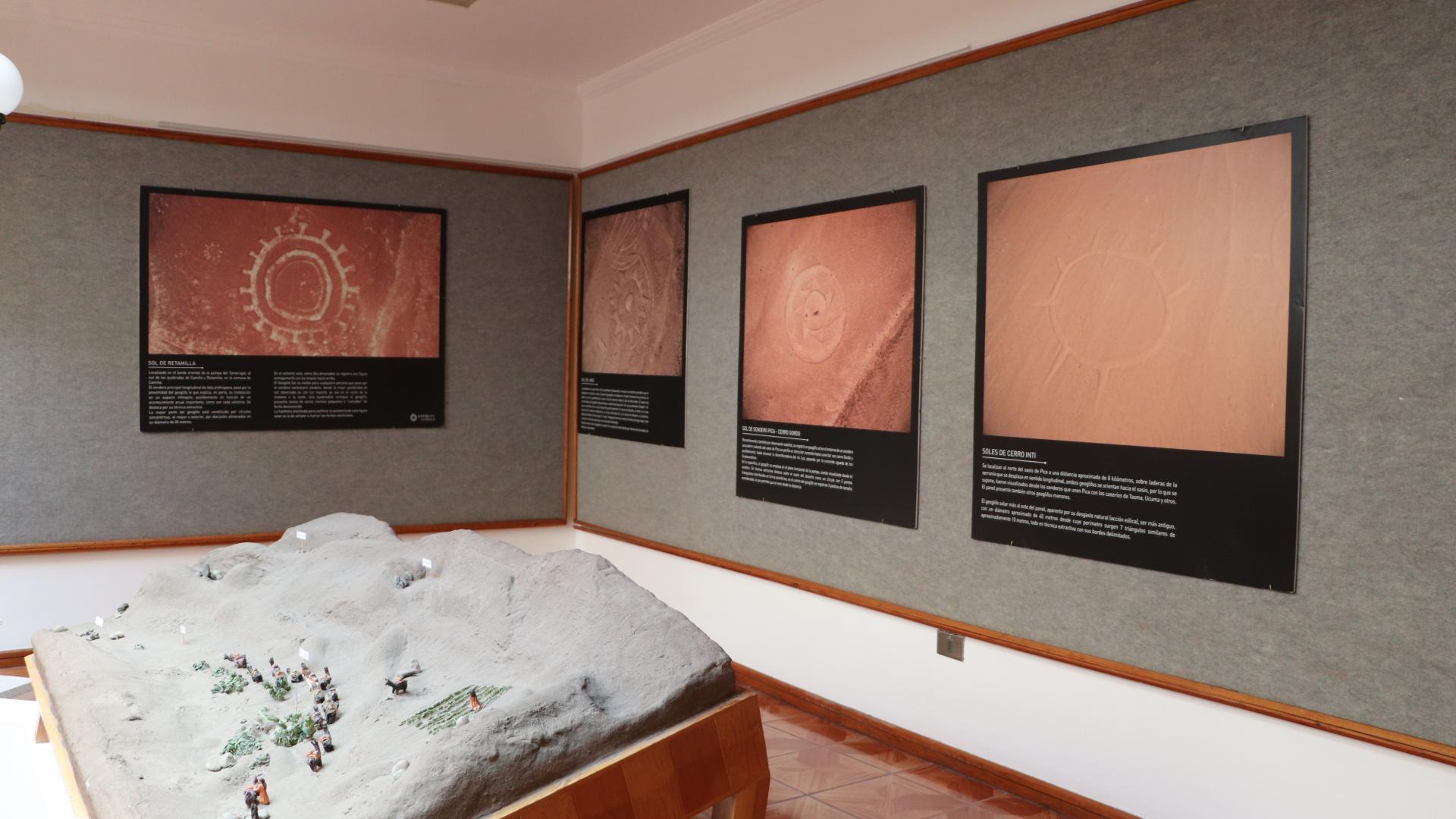 Interior museo: Exhibición de fotografía y maqueta de sitio arqueológico