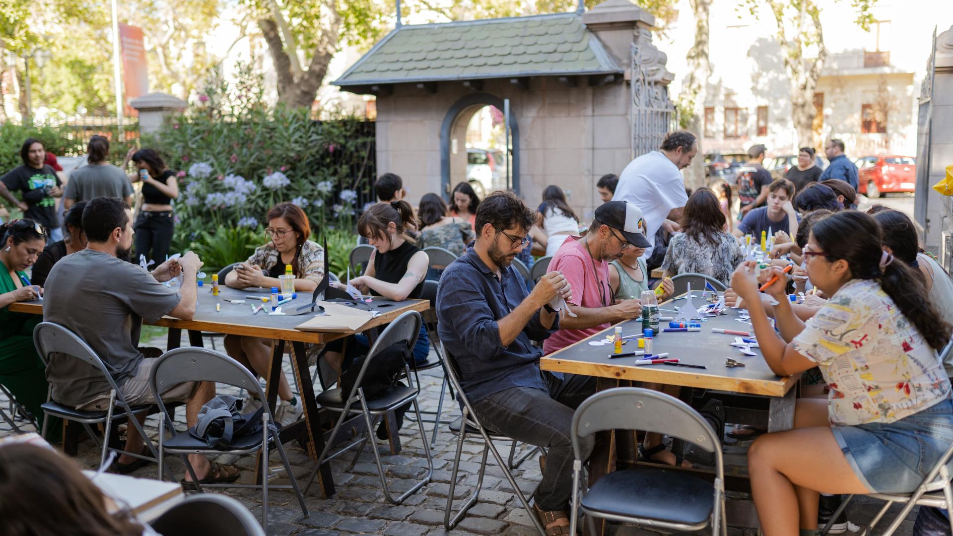 Personas sentadas en mesones trabajando con esculturas de papel 