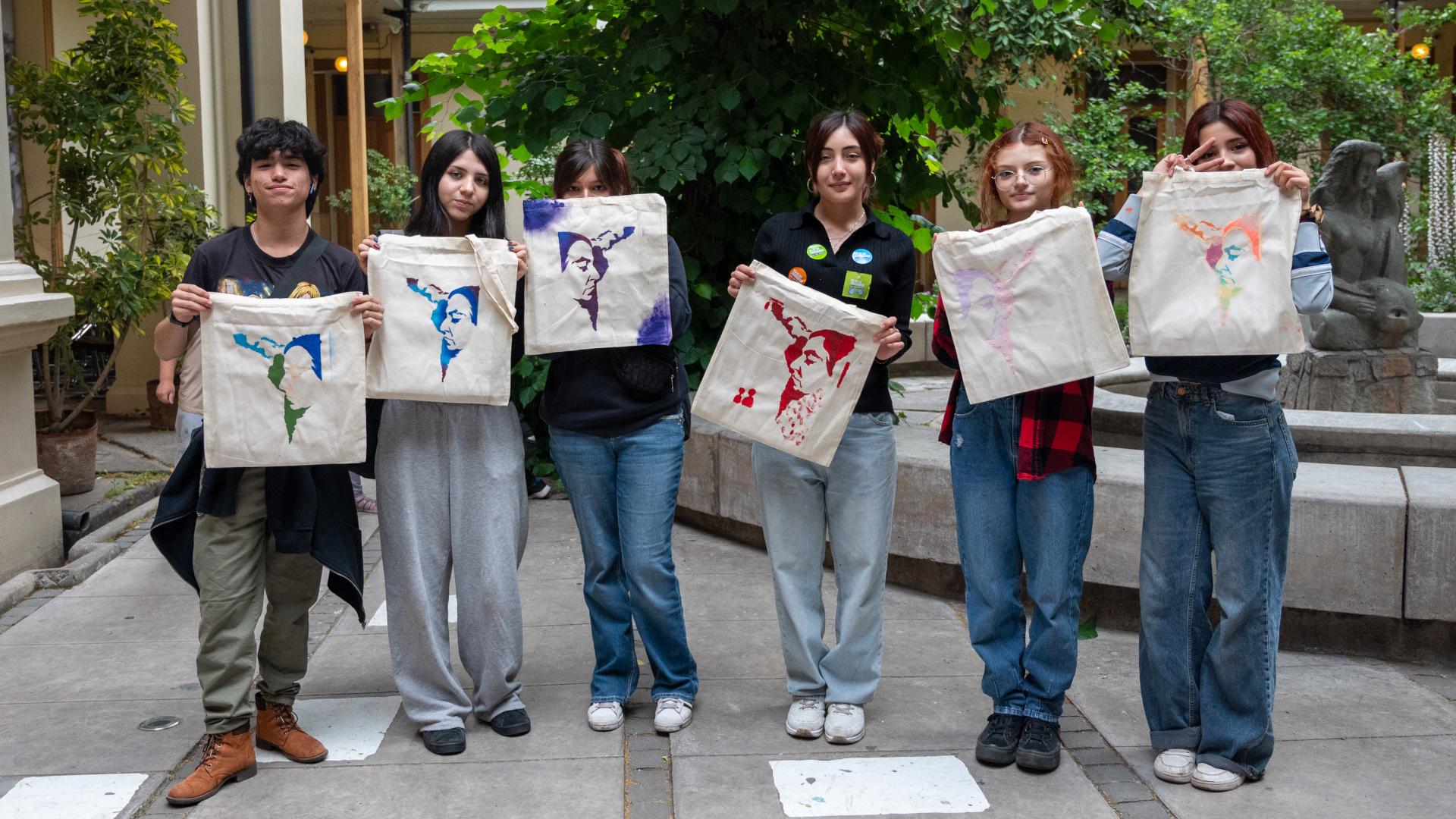Grupo de jóvenes posando con mochilas realizadas en el taller de esténcil