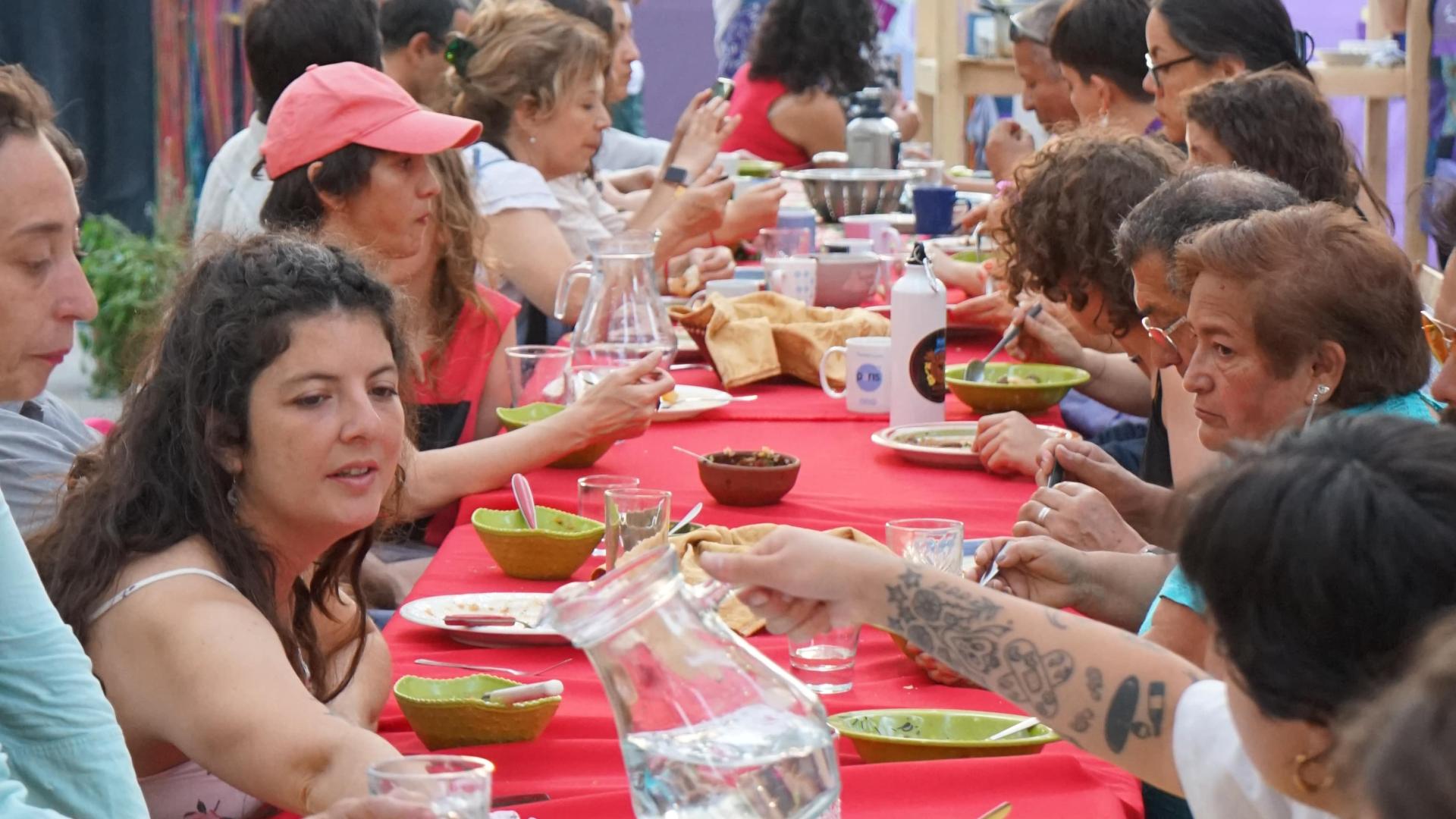 Personas comparten un cena comunitaria. Se sirven agua y comen en conjunto.