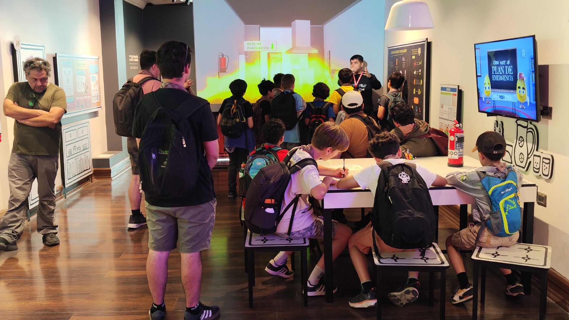 Grupo de niños y jóvenes en la sala interactiva ZIM MuBo, aprendiendo sobre prevención de incendios.