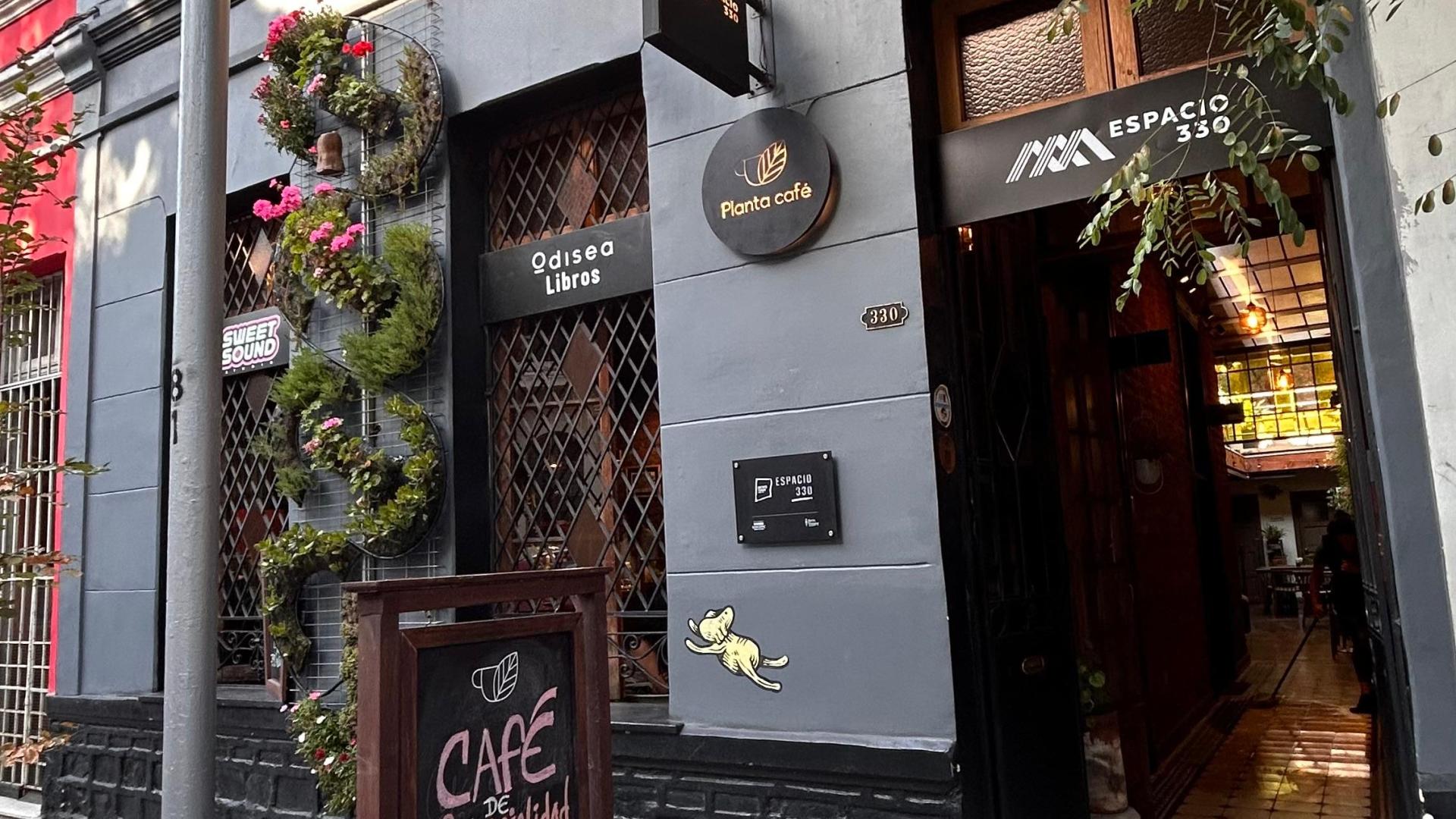 Fachada de Espacio 330, se ve la casa de fachada continua, tiene un jardín vertical y letreros negros con los logos de los emprendimientos que están dentro. 