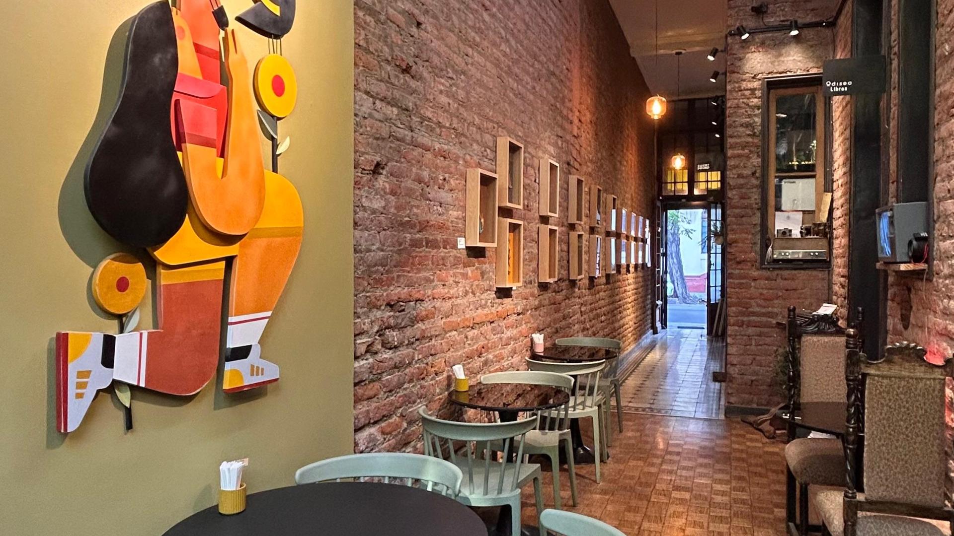 Vista desde el interior de Espacio 330, al costado izquierdo de la imagen el pasillo de ladrillo con las obras montadas, hay una instalación de madera de gran formato, además de sillas y mesas del café 