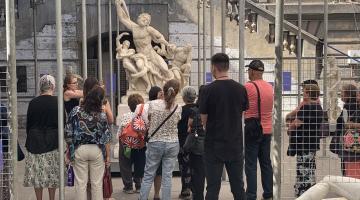 Grupo de personas que participa de un recorrido mediado en Patio Paulonia, se encuentran junto a la escultura Laocoonte y sus hijos, copia en mármol de esta obra clásica.